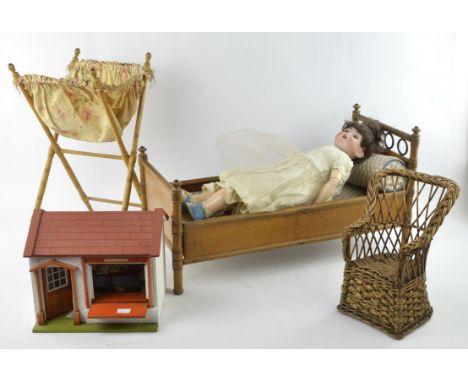 An early 20th century dolls beech and pine day bed with canopy, 65cm wide, a German bisque head doll with jointed composite b