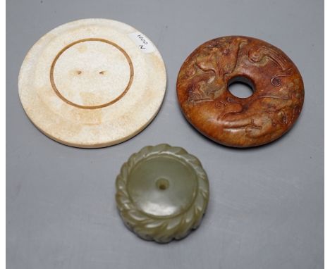 A Chinese green jade 'cash' pendant, a russet jade bi-disc and a burnt jade circular plaque