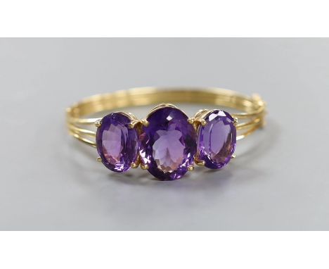 A modern 14k and three stone oval cut amethyst set hinged bangle, interior diameter 54mm, gross weight 24.8 grams.