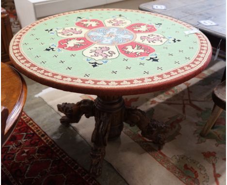 An early 20th century Continental carved oak circular centre table with heraldic tapestry top on winged lion supports, diamet