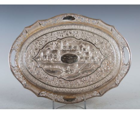 An early 20th century Indian silver presentation tray, decorated with a central panel of pavilions and palm trees within a sc