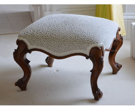 A Victorian mahogany stool, the stuffover upholstered seat raised on scroll and foliate carved cabriole supports, 63cm wide x
