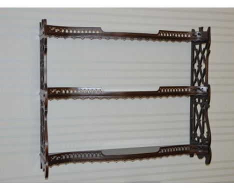 A George III style mahogany serpentine hanging shelf, the open shelves with pierced galleries enclosed by pierced fret work s