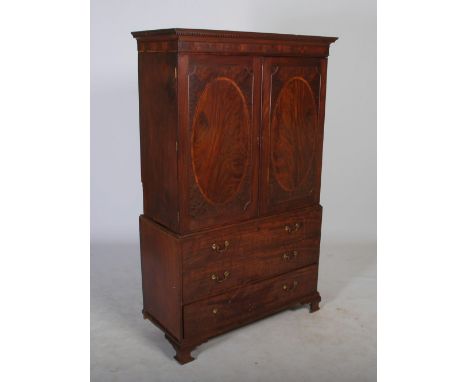 A George III mahogany and boxwood lined linen press, the moulded cornice and dentil frieze above a pair of cupboard doors, op
