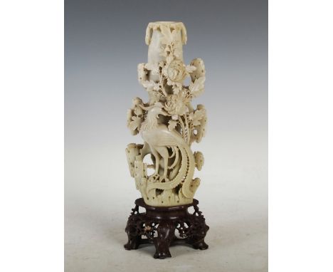 A Chinese soapstone candlestick, early 20th century, carved with phoenix, peony and foliage, on a pierced naturalistic base, 