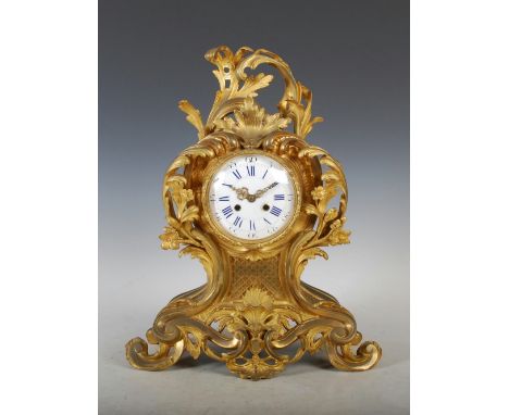 A late 19th century French Rococo style ormolu mantle clock, the circular enamel dial with Arabic and Roman numerals and twin