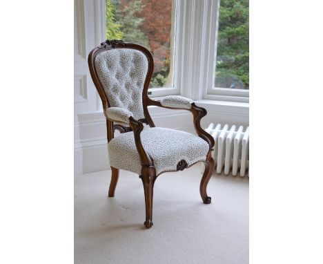 A Victorian rosewood armchair, with button down upholstered back, arms and seat, raised on cabriole supports with scroll carv