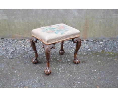 An early 20th century mahogany dressing table stool, the needlework upholstered seat raised on four acanthus carved cabriole 