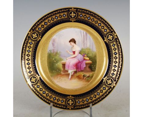 A Vienna porcelain cobalt blue ground hand painted cabinet plate decorated by A. HEER, depicting a young girl sitting on a be