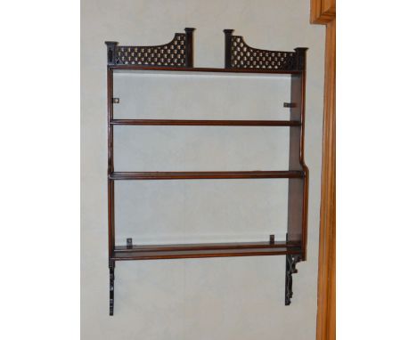 A George III style mahogany hanging shelf, the pierced gallery above three open shelves, supported on scroll carved brackets,