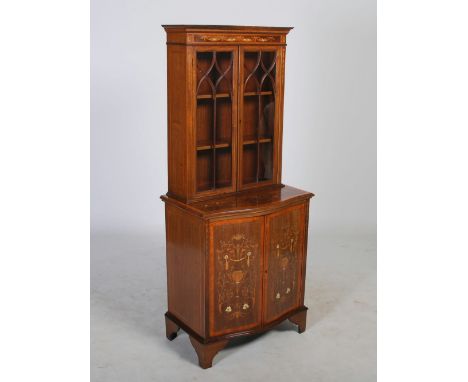 An Edwardian mahogany and satinwood banded bookcase, the moulded cornice above a ribbon tie and floral garland frieze, over t