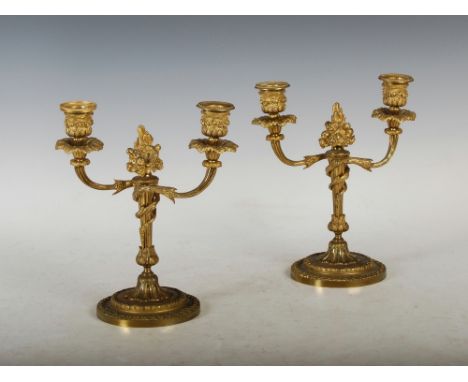 A pair of late 19th/ early 20th century ormolu two light candelabra, the foliate cast urn shaped nozzles with detachable drip