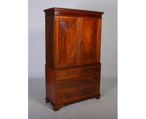 An Edwardian mahogany and satinwood banded linen press, the moulded cornice and dentil frieze above a pair of panelled cupboa