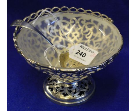 Silver pierced scroll design pedestal bowl with swing handle and glass liner together with plated pierced tea strain ladle. (