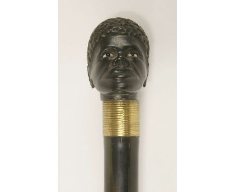 An ebonised walking stick,early 20th century(?), carved with an African head, the shaft unscrewing to reveal an ivory-handled