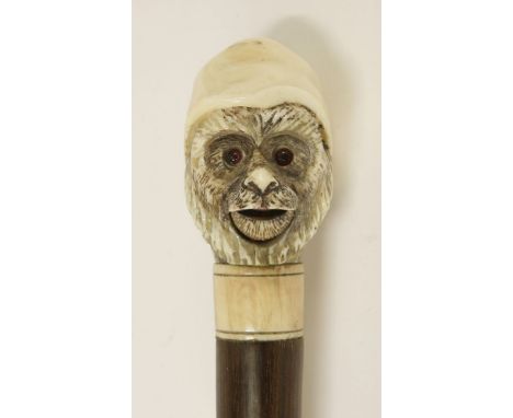 A rosewood walking stick,early 20th century(?), carved with an ivory automaton monkey's head, his eyes change, his  mouth ope