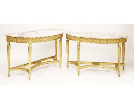 A pair of Adam-style giltwood console tables, late 20th century, of demilune form, with veined white marble tops on turned su