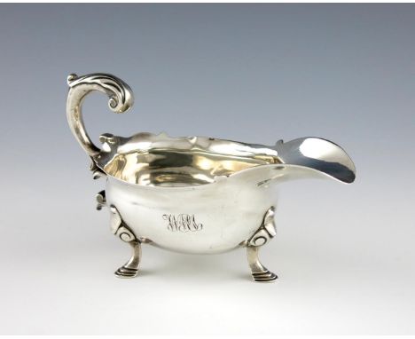 A George II silver sauce boat, maker's mark worn, London 1745, oval form, wavy-edge border, leaf capped scroll handle, on thr