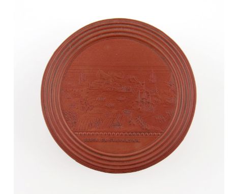 λA 19th century French red Bois Durci snuff box, circular form, the pull-of cover pressed with a scene of the siege of Gibral