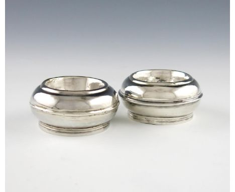 Two similar early 18th century silver salt cellars, marks worn, circular cushion form, on raised circular foot, one engraved 