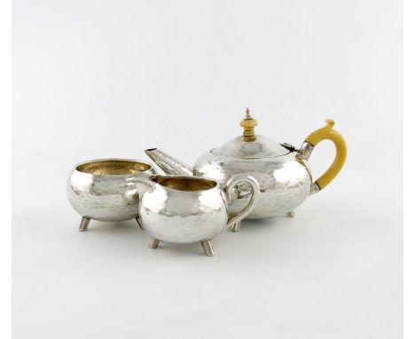 λA three-piece Edwardian Arts and Crafts silver bachelor's tea set, by Nathan and Hayes, Chester 1909, circular form, ivory s