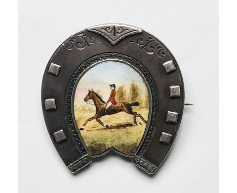 Late Victorian silver brooch in the form of a horseshoe, the centre enamel decorated with horse and rider (Birmingham, Willia