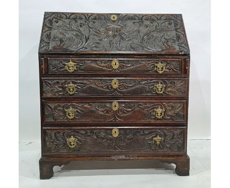 Victorian carved oak bureau, the fall heavily carved with green man decoration, the fall graduated carved drawers, raised on 