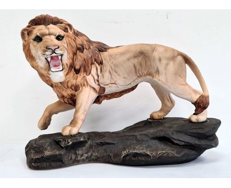 Beswick tinted bisque porcelain model lion on rockwork, 30cm wide 