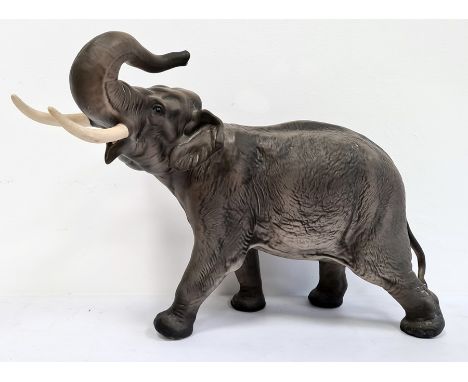 Beswick tinted bisque porcelain model of elephant with trunk raised, 41cm wide overall 