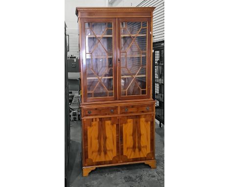 20th century yew bookcase cabinet with dentil cornice above astragal glazed doors enclosing shelves, two drawers and two cupb