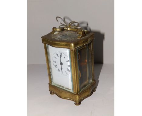A French brass carriage clock with serpentine top & base – damage to circular escapement window, 5” high excluding handle.