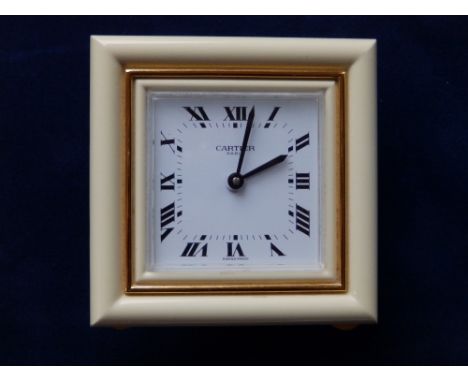 A cased modern Cartier quartz travelling clock, the square dial finished in white & gold with black hands and roman numerals,