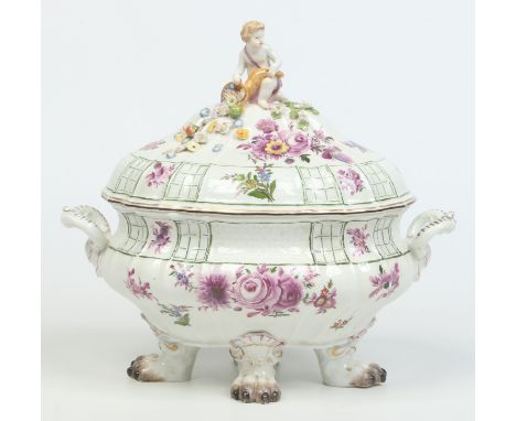 An 18th century Meissen tureen and cover. Surmounted with a putti finial modelled emptying a cornucopia of fruit and flowers 