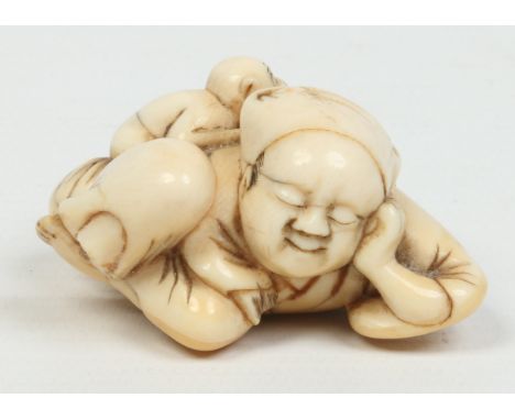 A Japanese Edo period carved ivory netsuke on hardwood plinth. Formed as a sleeping man with a monkey behind his back stealin