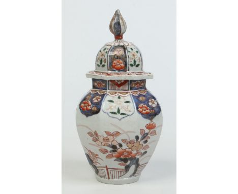 A Japanese Imari octagonal baluster jar and cover. With moulded panel collar and painted with a landscape incorporating a fen