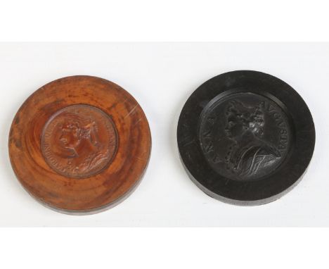 Two 18th century carved draughts counters. One ebony with a portrait of Queen Anne, the other of boxwood with a portrait of Q