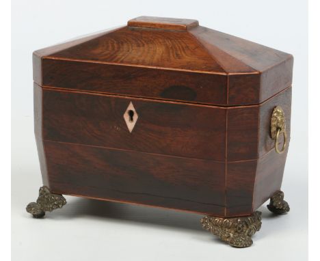 A Regency rosewood tea caddy of canted rectangular form. With brass lion mask handles and raised on bracket feet, 21.75cm wid