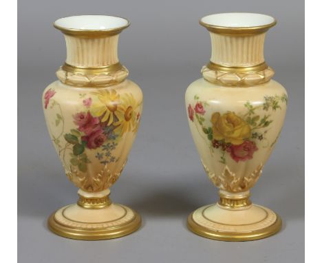 A pair of Royal Worcester blush ground specimen vases, edged in gilt and painted with flowers. Printed puce marks, date codes