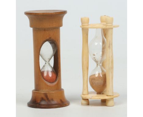 A carved bone and glass egg timer and a treen example. Largest 8.75cm.