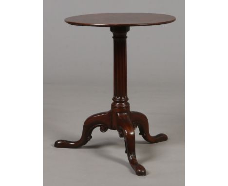 A Georgian mahogany tripod wine table. With reeded tapering column raised on scroll carved supports, 55cm high, top 44.5cm di