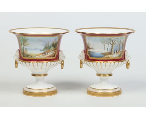 A pair of Royal Worcester pedestal vases with moulded lion maask handles by Frank Clark. Claret ground, with tooled gilding a