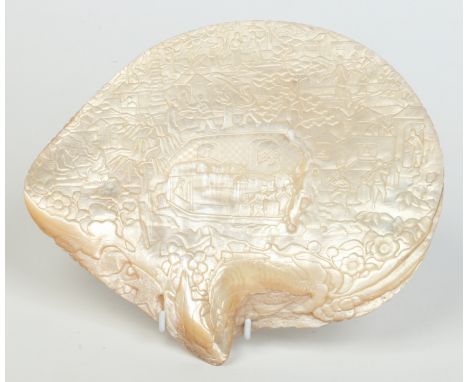 A 19th century Cantonese carved mother of pearl shell depicting a bustling harbour scene with figures trading, playing cheque