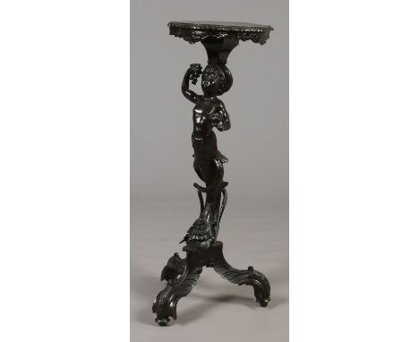 A 19th century Italian ebonized and carved walnut Blackamoor torchere. With a serpentine gadroon top raised on a central colu