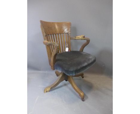 An early 20th century oak swivel desk chair, raised on ceramic castors, (one foot broken - needs restoration), H.84cm 