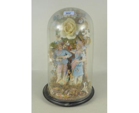 A continental porcelain display of two figures with ceramic flowers under a glass dome, 39cm tall