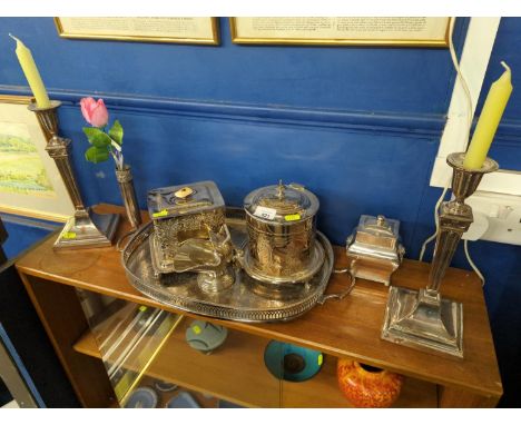 Silver plated items on shelf Inc. candle sticks,  biscuit barrel and tray. 