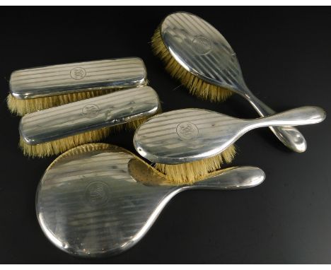A silver mounted George V dressing table set, comprising mirror, four brushes, each with an engine turned decoration and mono