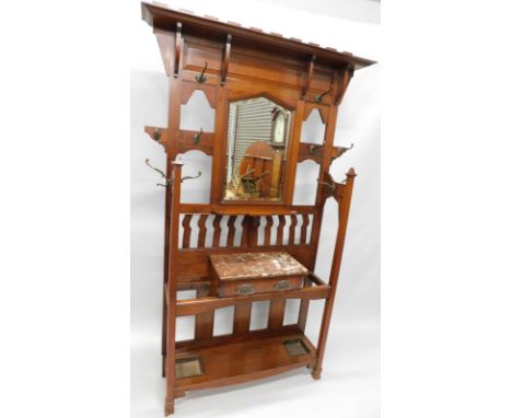 A late Victorian walnut hall stand, the crenellated top with a shelf above an arched bevelled mirror plate, surrounded by bra