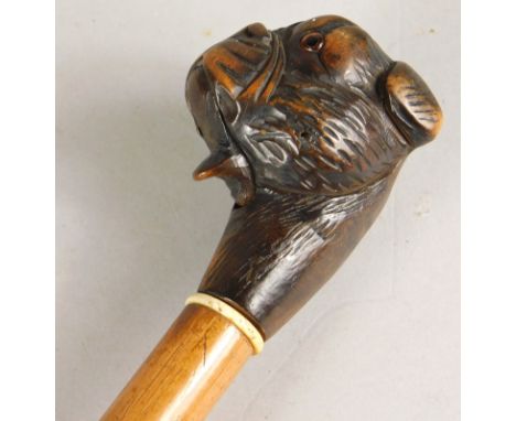 An early 20thC walking stick, the handle carved in the form of a mastiff type dog, with glass eyes and a hinged mouth, 90cm l