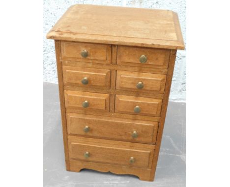 A miniature hardwood chest of drawers, the top with a moulded edge, above an arrangement of six short and two long drawers, e